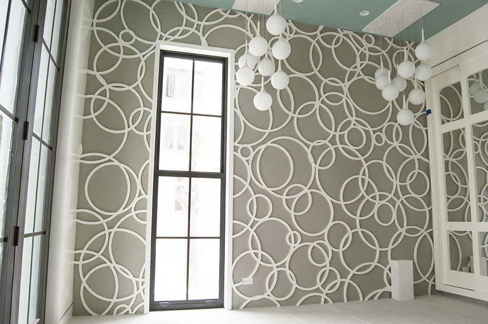 Molding of white overlapping circles of various sizes on a dark grey wall.